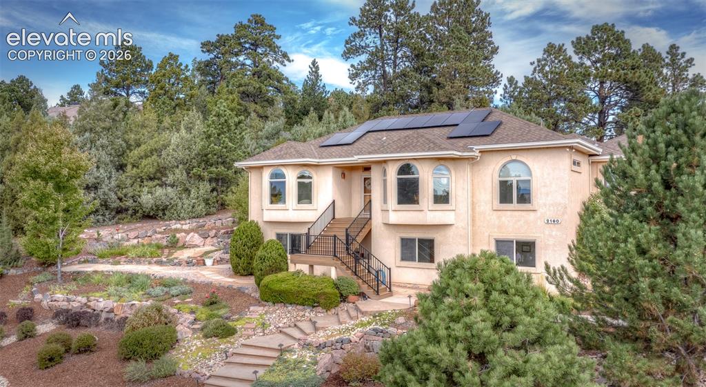 Image 43 of 50: Stucco exterior with multiple arched windows and solar panels