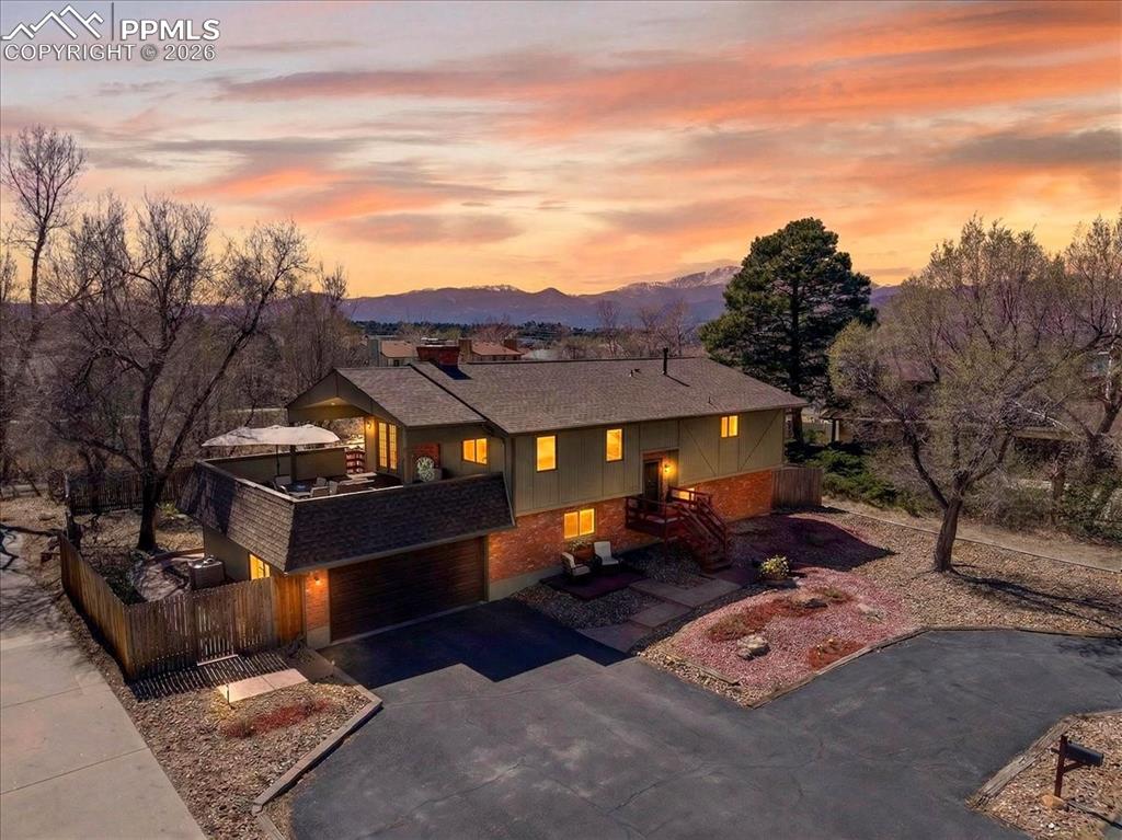 Caption: View of front of house with asphalt driveway, brick siding, an attached garage, a patio area, and a 