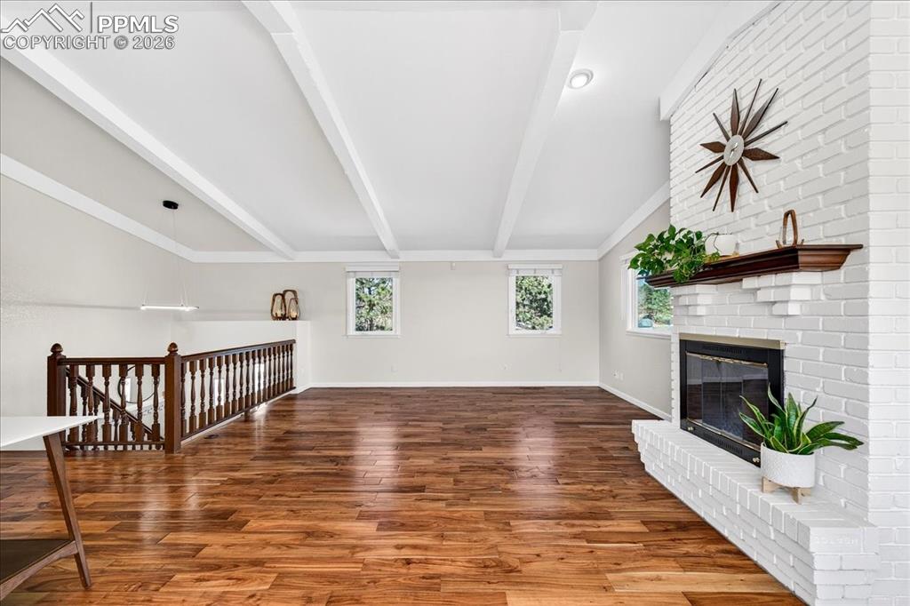 Image 12 of 48: Unfurnished living room with dark wood-type flooring, a brick fireplace, pl
