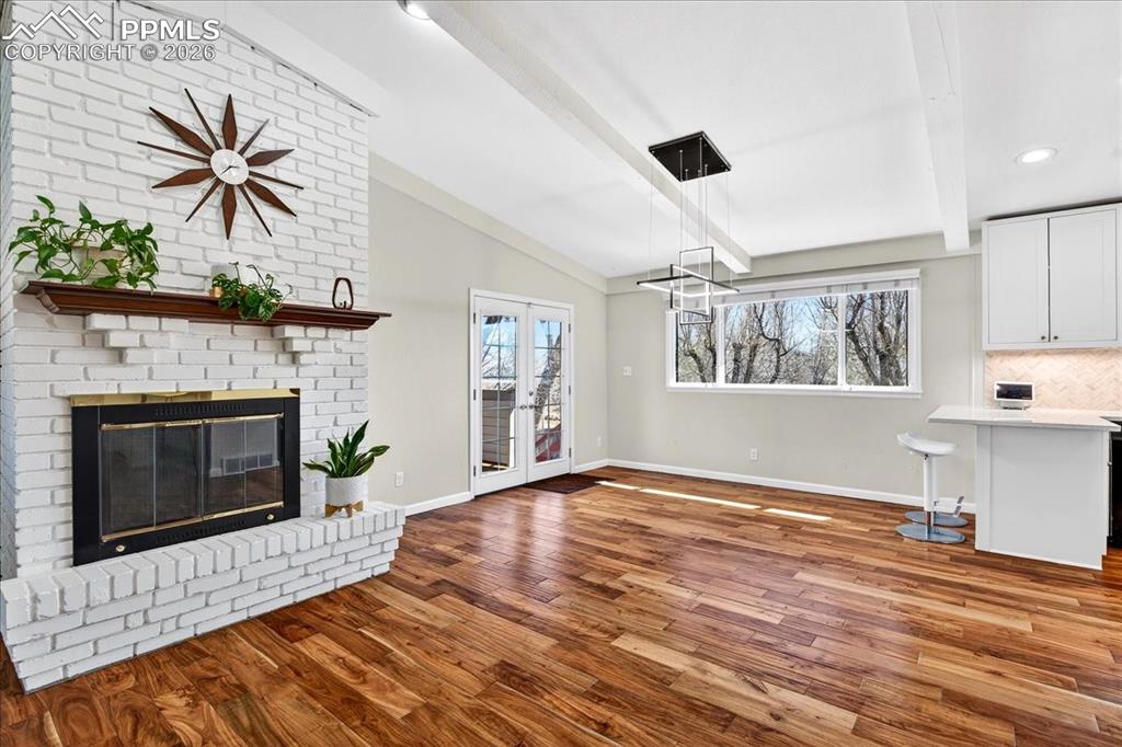 Image 2 of 48: Unfurnished living room with wood finished floors, a brick fireplace, lofte