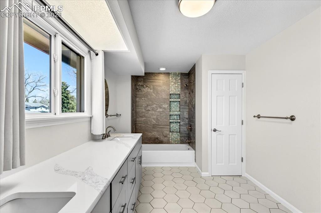 Image 21 of 48: Bathroom with double vanity and shower / washtub combination