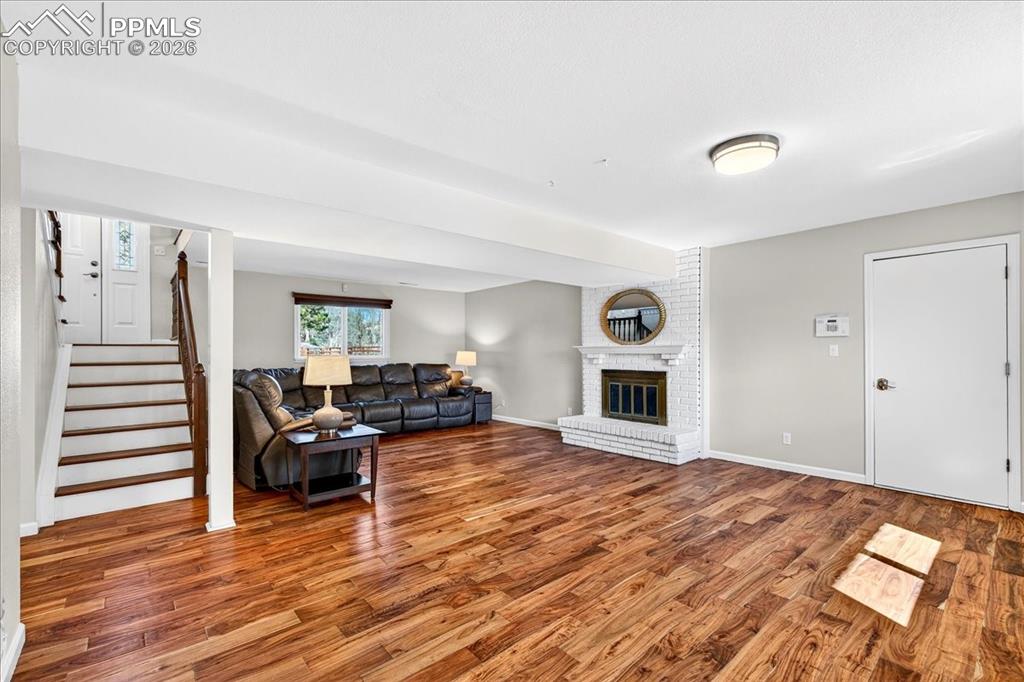Image 22 of 48: Living area featuring wood finished floors and a brick fireplace