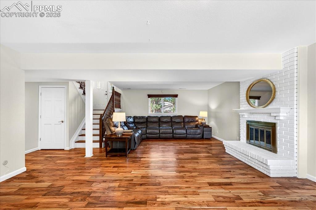 Image 23 of 48: Living room featuring wood finished floors and a brick fireplace