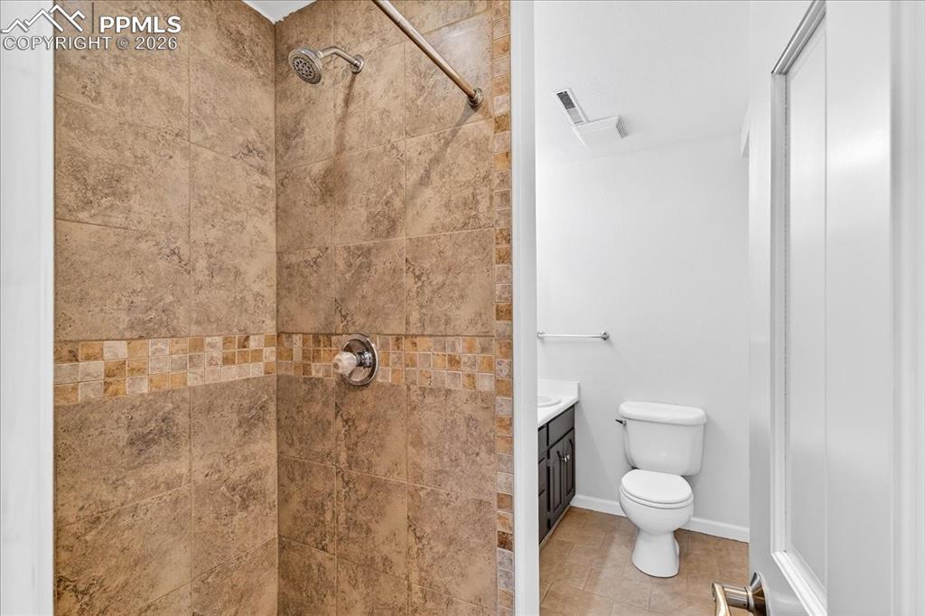Image 29 of 48: Full bathroom with vanity, a tile shower, and light tile patterned floors