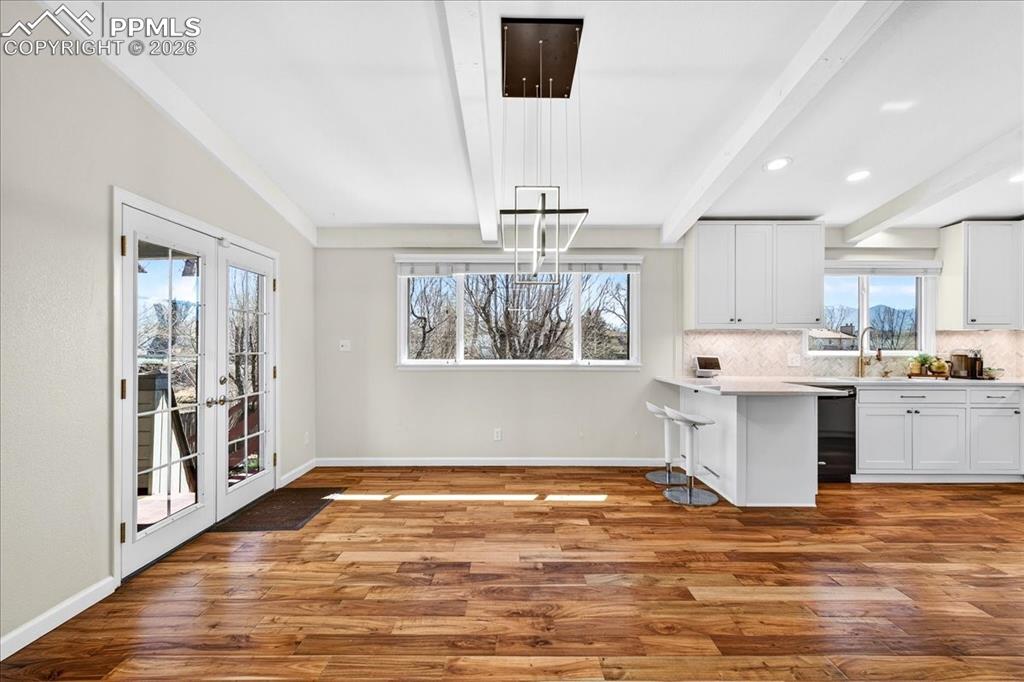 Image 3 of 48: Unfurnished dining area with light wood finished floors, beamed ceiling, an