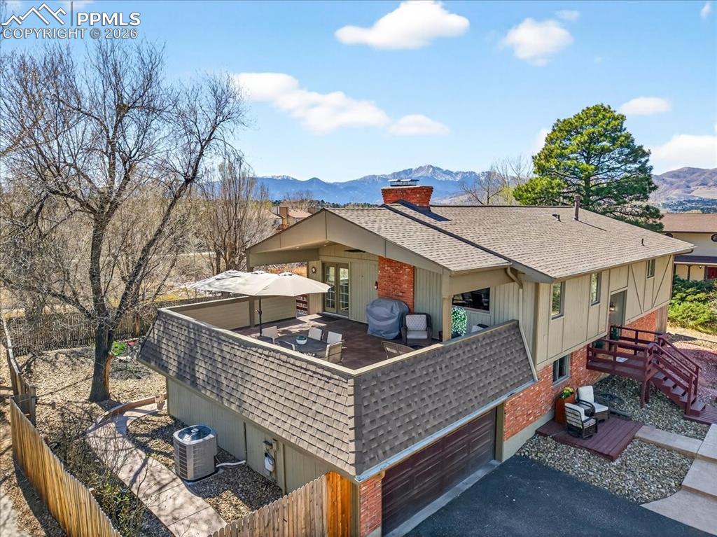 Image 31 of 48: Back of house with a shingled roof, brick siding, a mountain view, and a ch