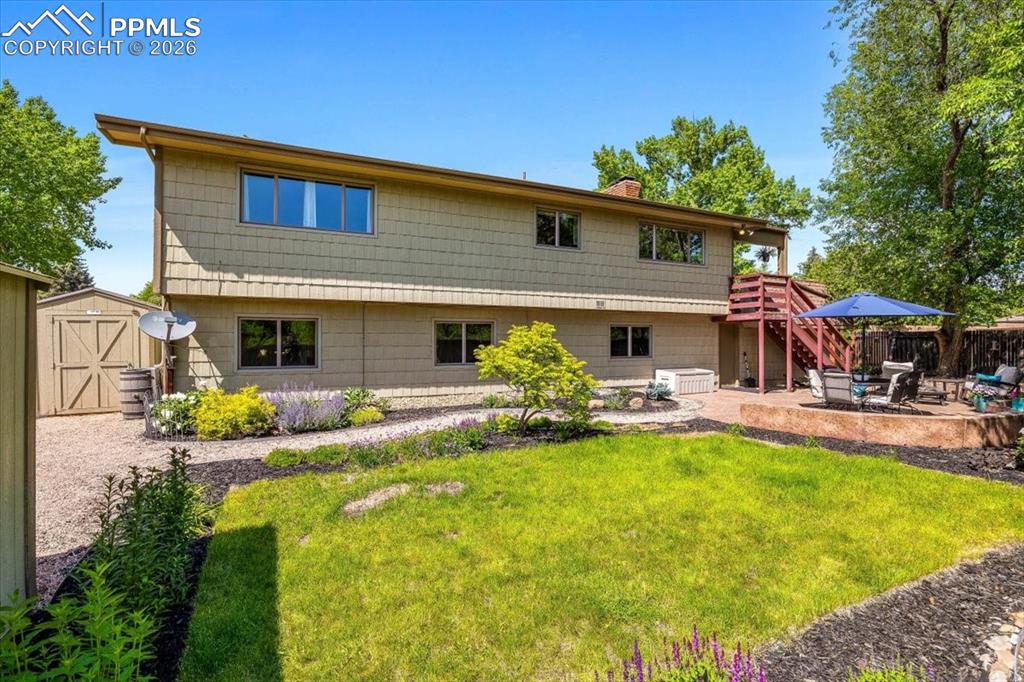 Image 38 of 48: Rear view of house featuring a patio area, a storage shed, and a chimney