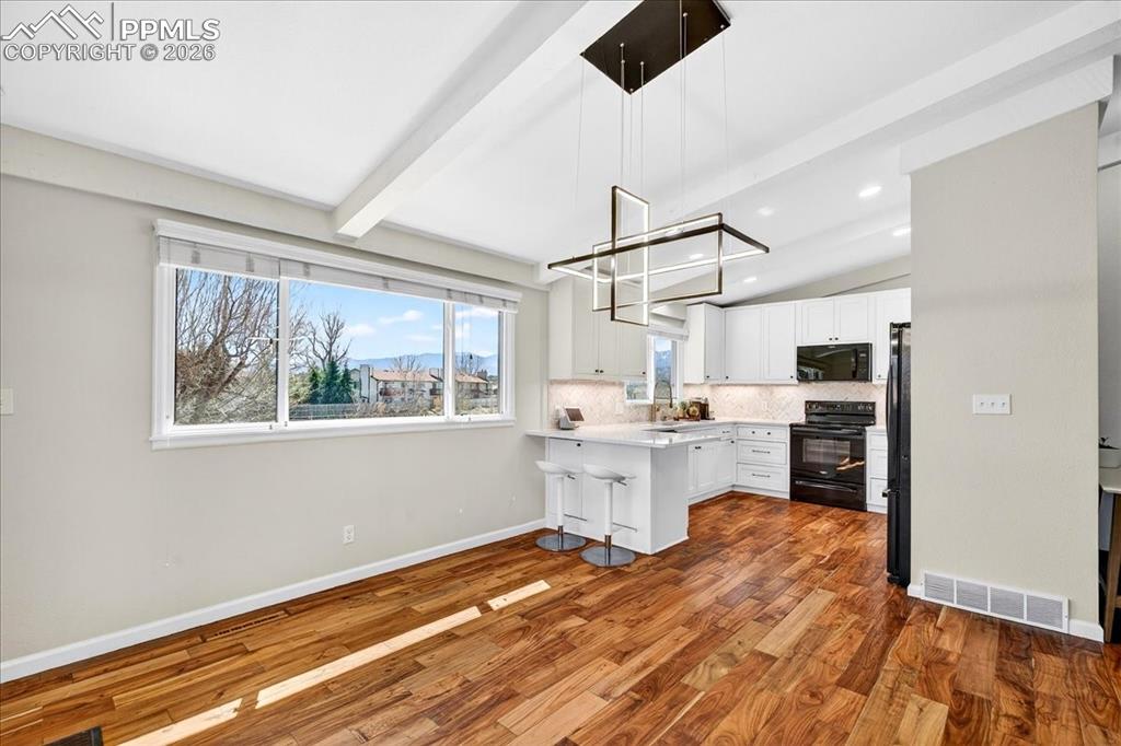 Image 4 of 48: Kitchen with light countertops, lofted ceiling with beams, dark wood-type f