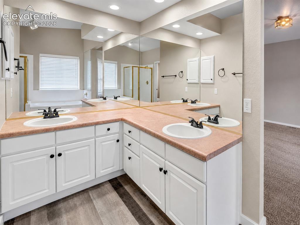 Image 12 of 25: Bathroom featuring a dual vanity with white cabinetry, integrated sinks, an