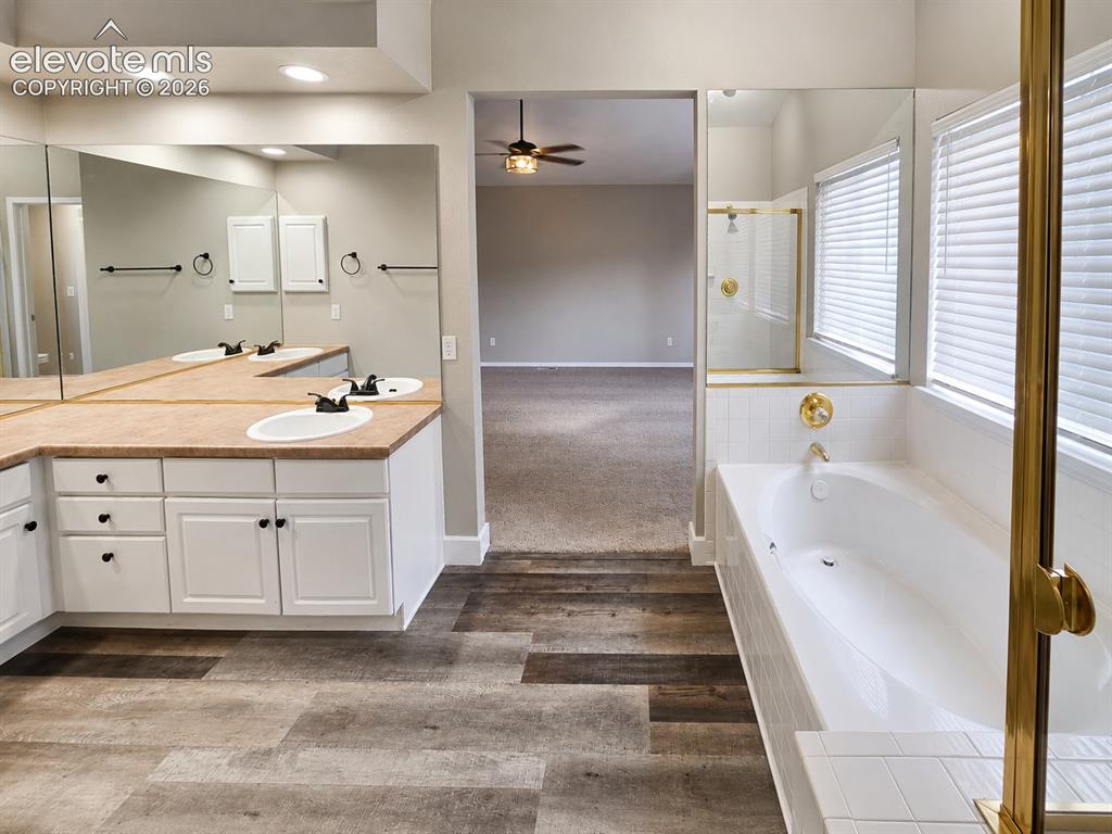 Image 13 of 25: Soaking tub with white tile surround, adjacent shower with gold-finish fram