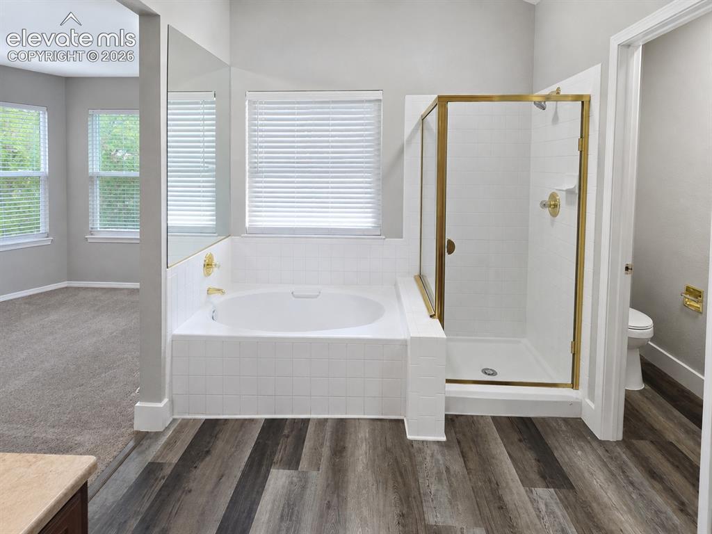 Image 15 of 25: Soaking tub with white tile surround, adjacent shower with gold-finish fram