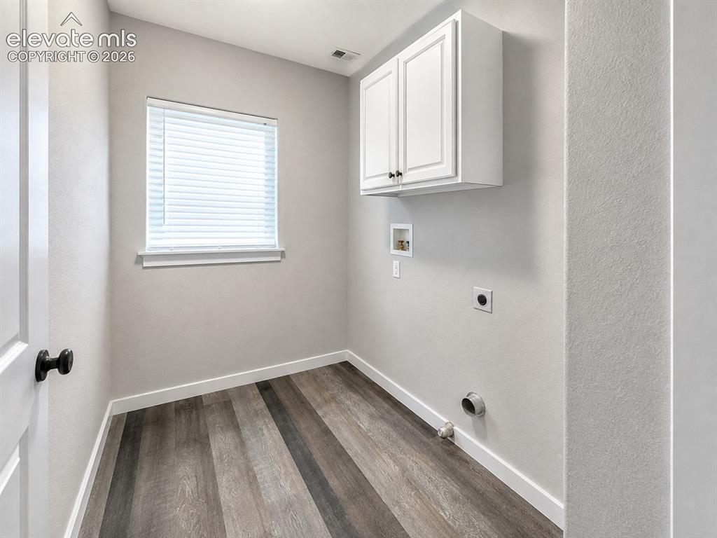 Image 16 of 25: Wood-finish flooring, white cabinetry, and a window with blinds