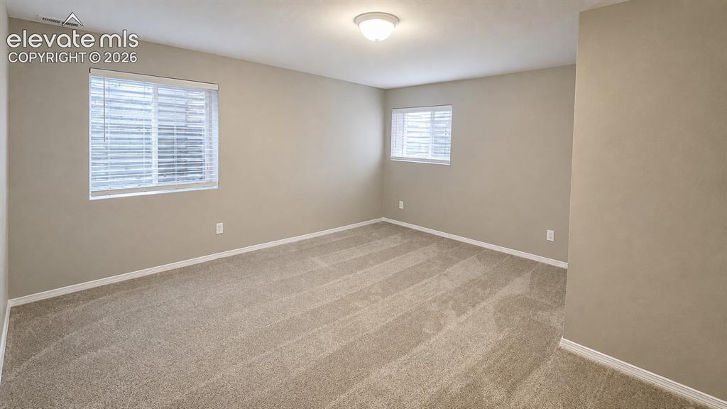 Image 19 of 25: Neutral paint palette, textured carpeting, multiple windows with blinds, an