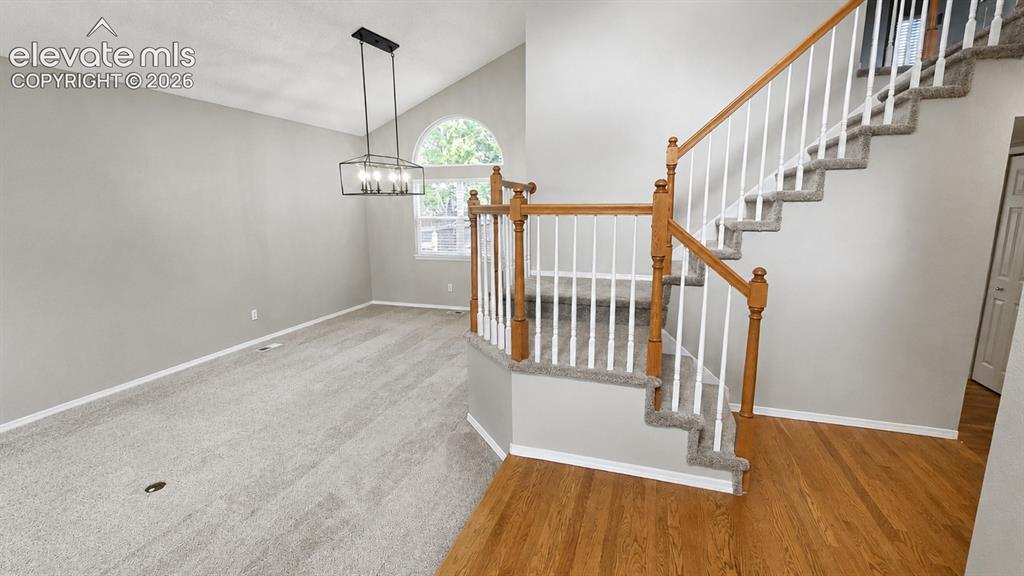 Image 5 of 25: Vaulted ceiling with an arched window, linear chandelier, hardwood flooring
