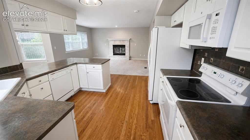 Image 6 of 25: Kitchen featuring white cabinetry, dark countertops, built-in dishwasher, a