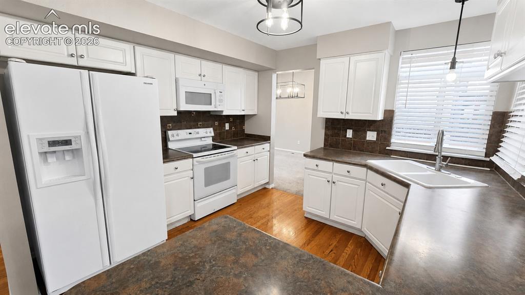 Image 7 of 25: White paneled cabinetry, wood-finish flooring, undermount sink, and recesse