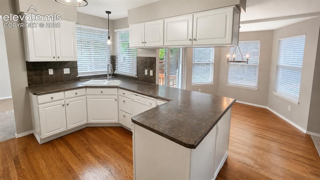 Image 8 of 25: Kitchen featuring white cabinetry, dark countertops, a built-in sink, and w