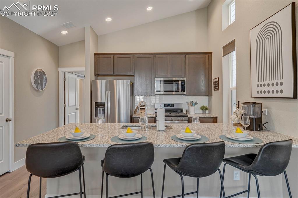 Image 17 of 42: Kitchen featuring a breakfast bar, decorative backsplash, appliances with s
