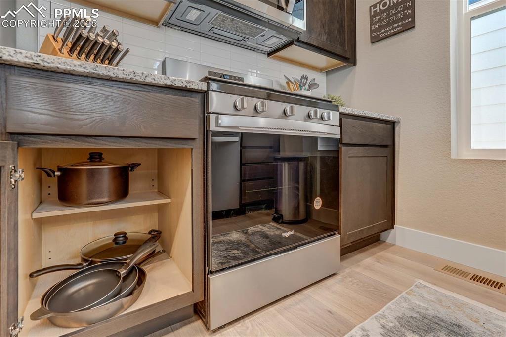 Image 21 of 42: Kitchen view of light wood-style floors, dark brown cabinets, stainless ste