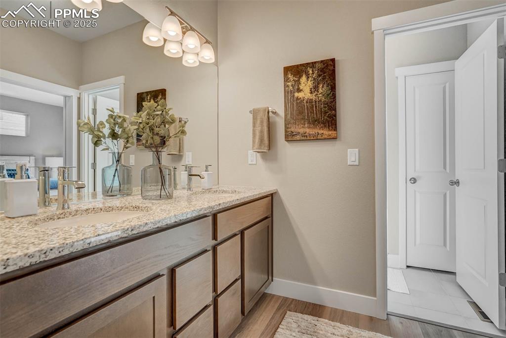 Image 29 of 42: Bathroom with double vanity and light wood-style flooring