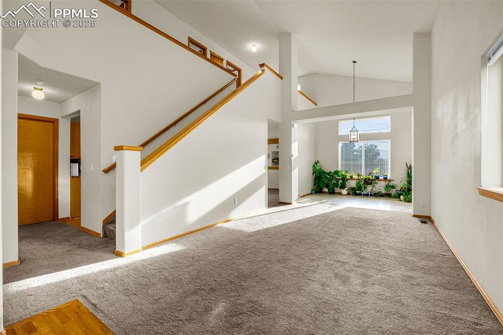 Image 11 of 40: Foyer with carpet floors, stairway, and lofted ceiling
