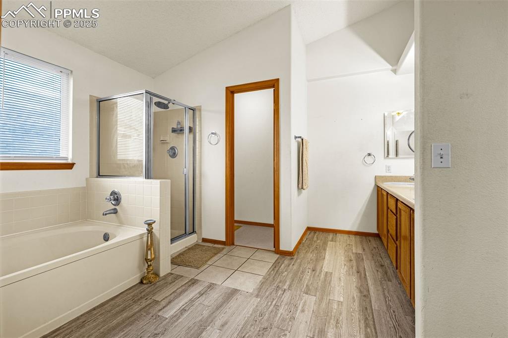 Image 14 of 40: Full bath with wood finished floors, vanity, a shower stall, a bath, and va