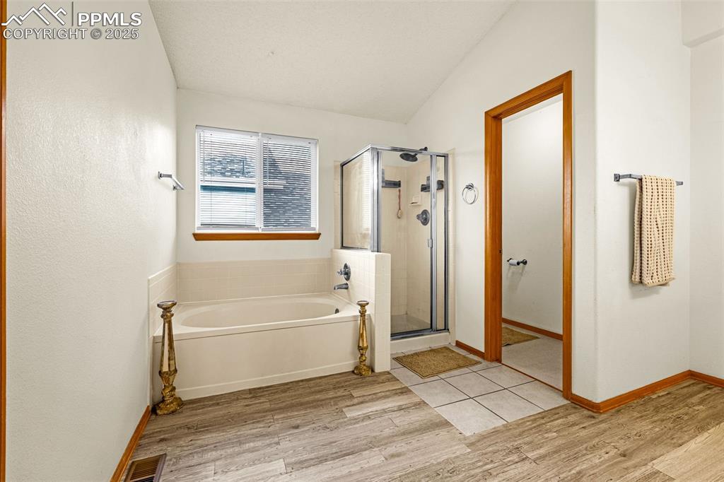 Image 15 of 40: Bathroom with a bath, wood finished floors, and a stall shower