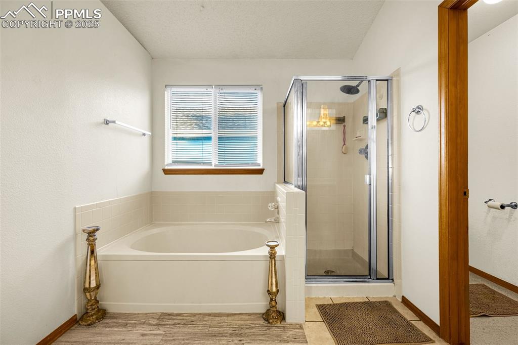 Image 16 of 40: Bathroom featuring a shower stall, a garden tub, wood finished floors, and 