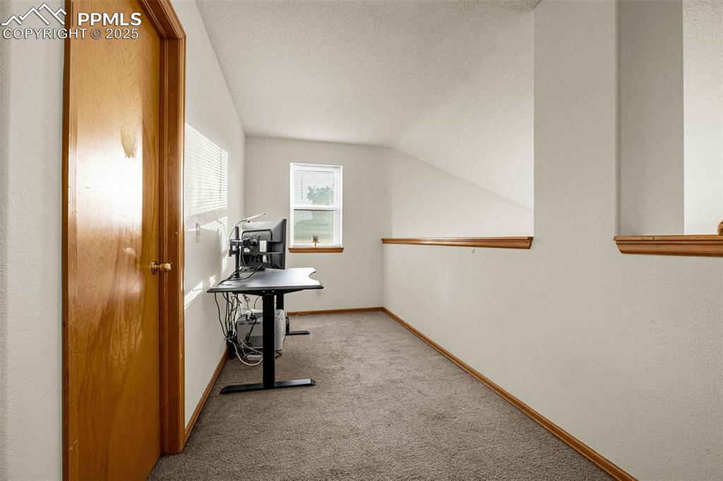 Image 26 of 40: Hall with carpet, lofted ceiling, and a textured ceiling