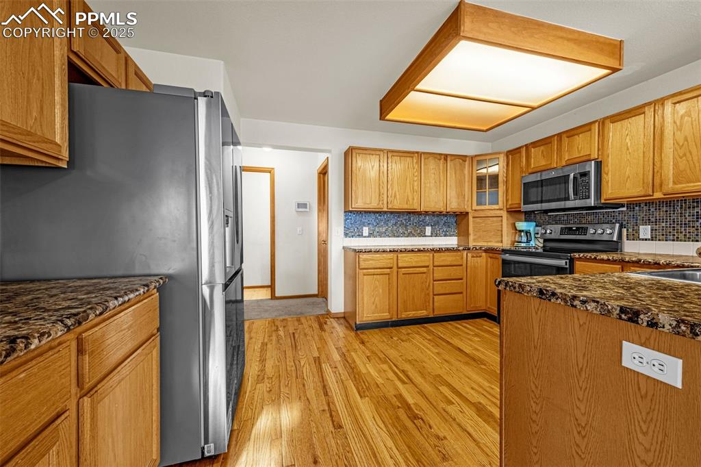 Image 5 of 40: Kitchen featuring stainless steel appliances, backsplash, light wood finish