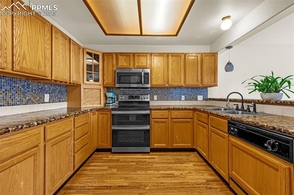 Image 6 of 40: Kitchen featuring appliances with stainless steel finishes, light wood-styl