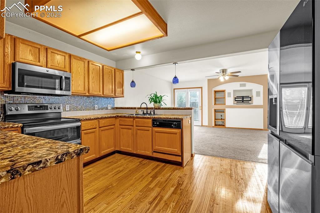 Image 7 of 40: Kitchen with appliances with stainless steel finishes, a peninsula, backspl