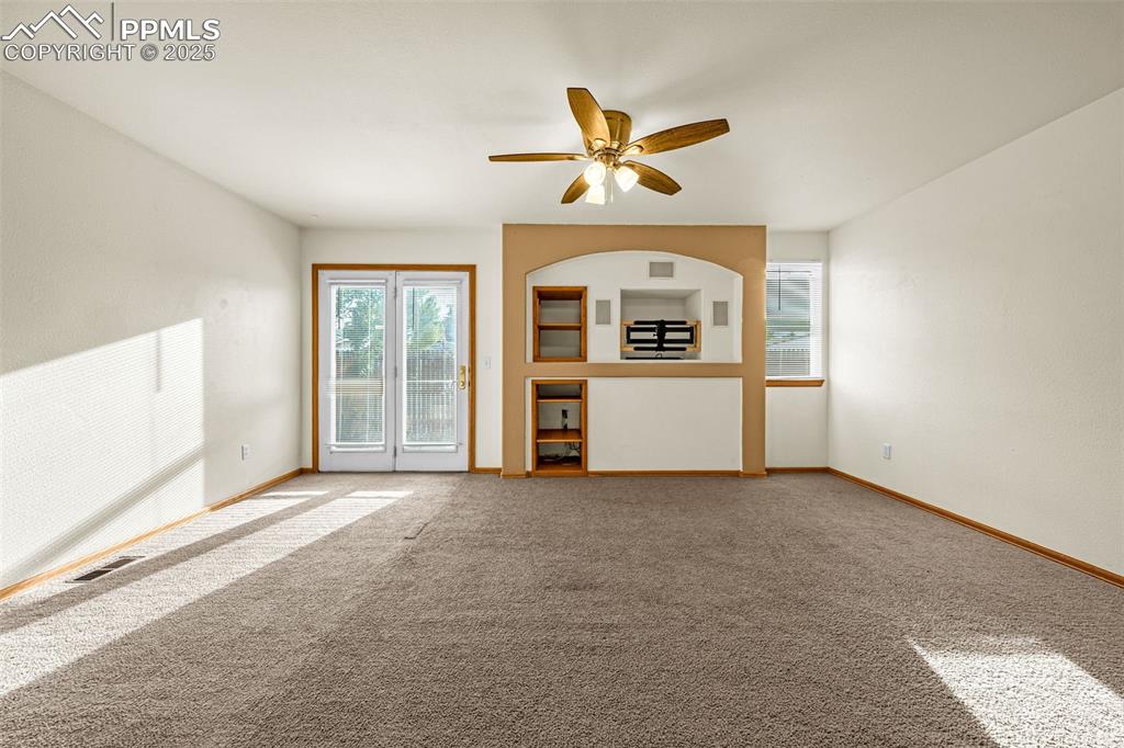 Image 8 of 40: Unfurnished living room featuring ceiling fan and carpet flooring