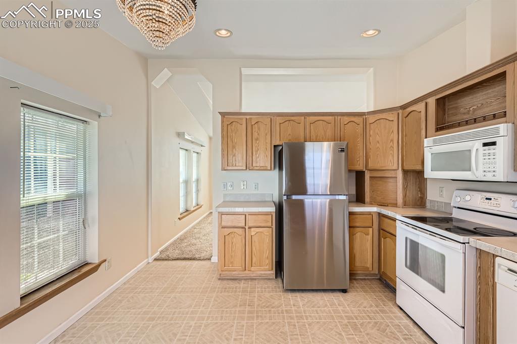 Image 11 of 28: Kitchen with white appliances, light countertops, recessed lighting, and a