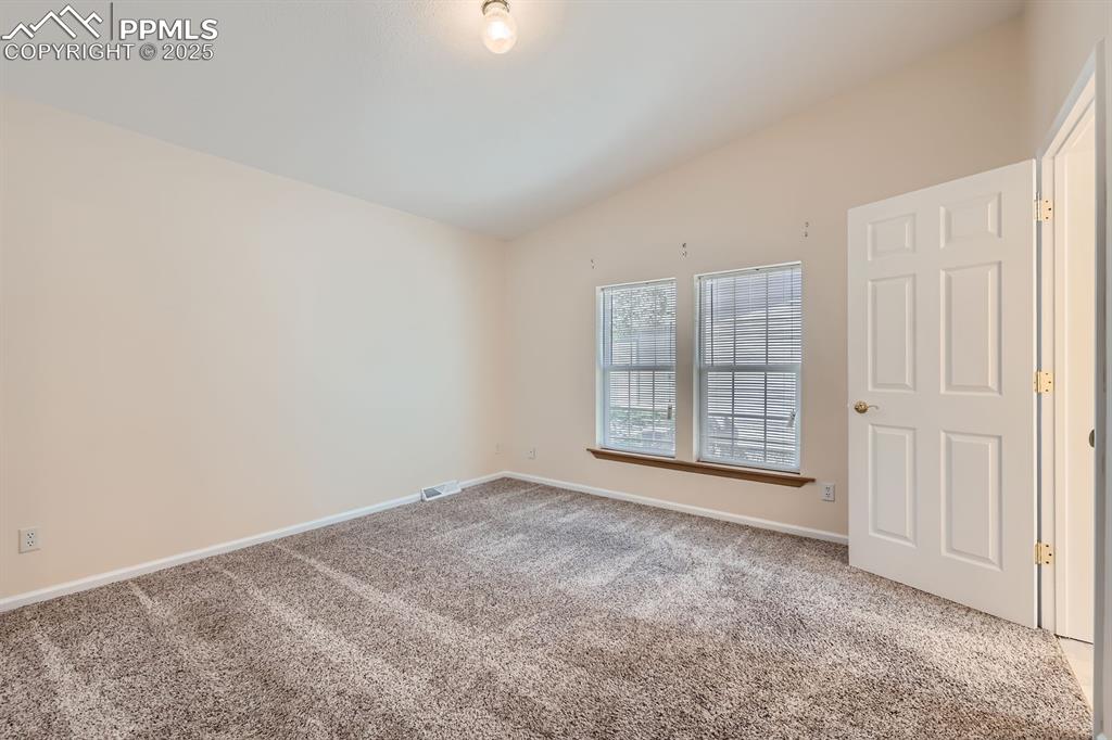 Image 13 of 28: Carpeted empty room with lofted ceiling and baseboards
