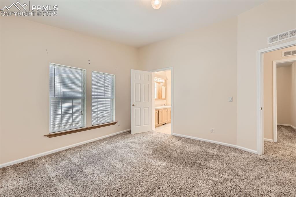 Image 14 of 28: Unfurnished bedroom with light carpet and ensuite bathroom