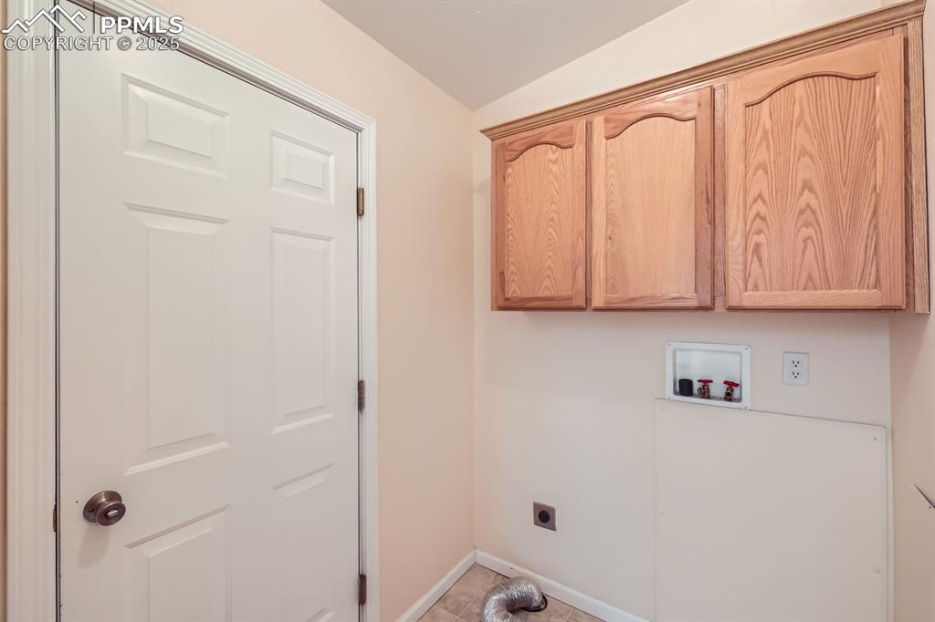 Image 24 of 28: Laundry room with hookup for an electric dryer, cabinet space, and washer h