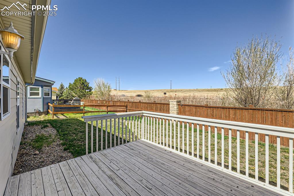 Image 25 of 28: Wooden deck with a fenced backyard