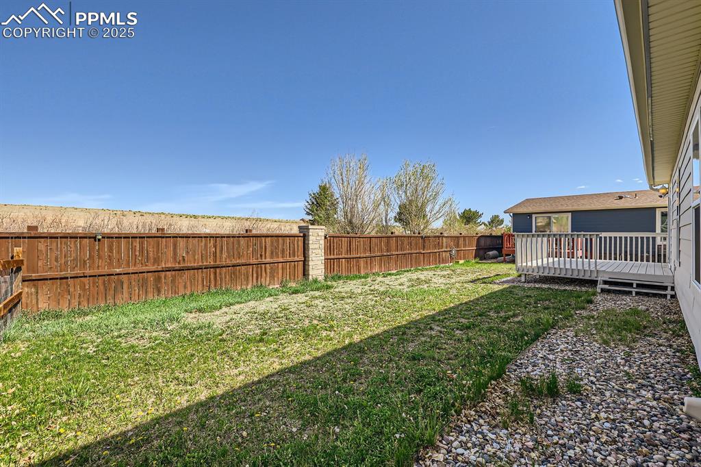 Image 26 of 28: Fenced backyard with a wooden deck