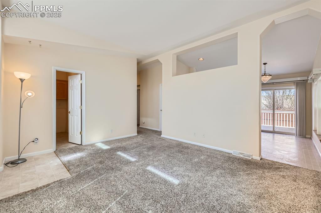 Image 6 of 28: Spare room featuring carpet flooring, lofted ceiling, and tile patterned fl