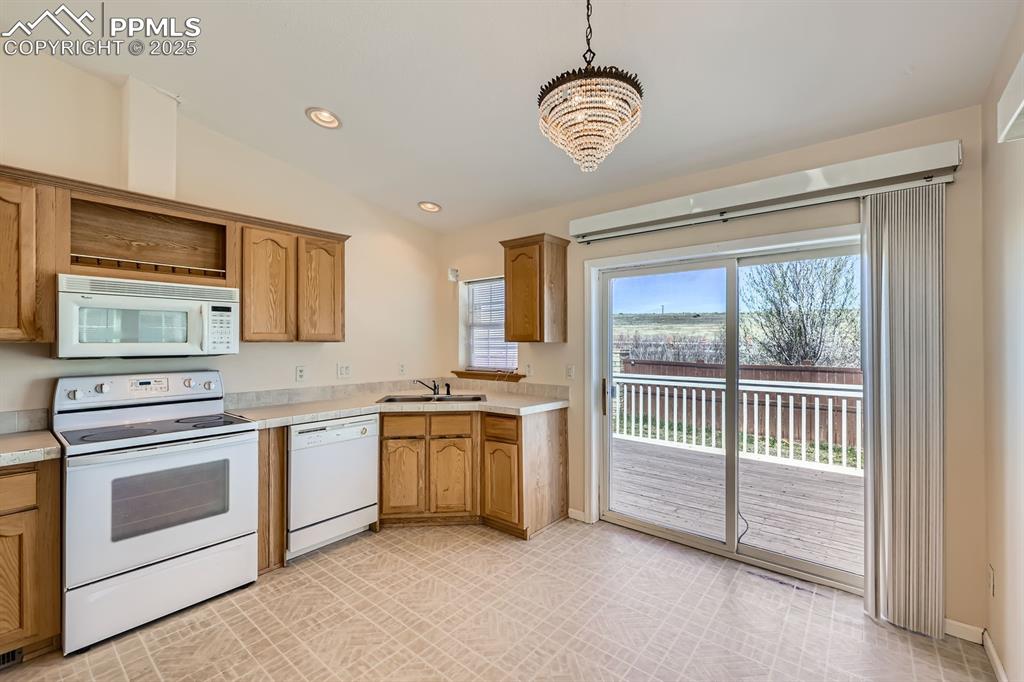 Image 8 of 28: Kitchen featuring vaulted ceiling, white appliances, light countertops, a c