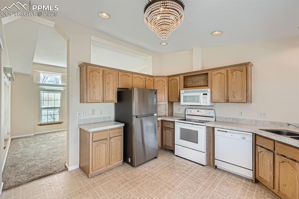 Image 9 of 28: Kitchen featuring white appliances, light countertops, a chandelier, recess