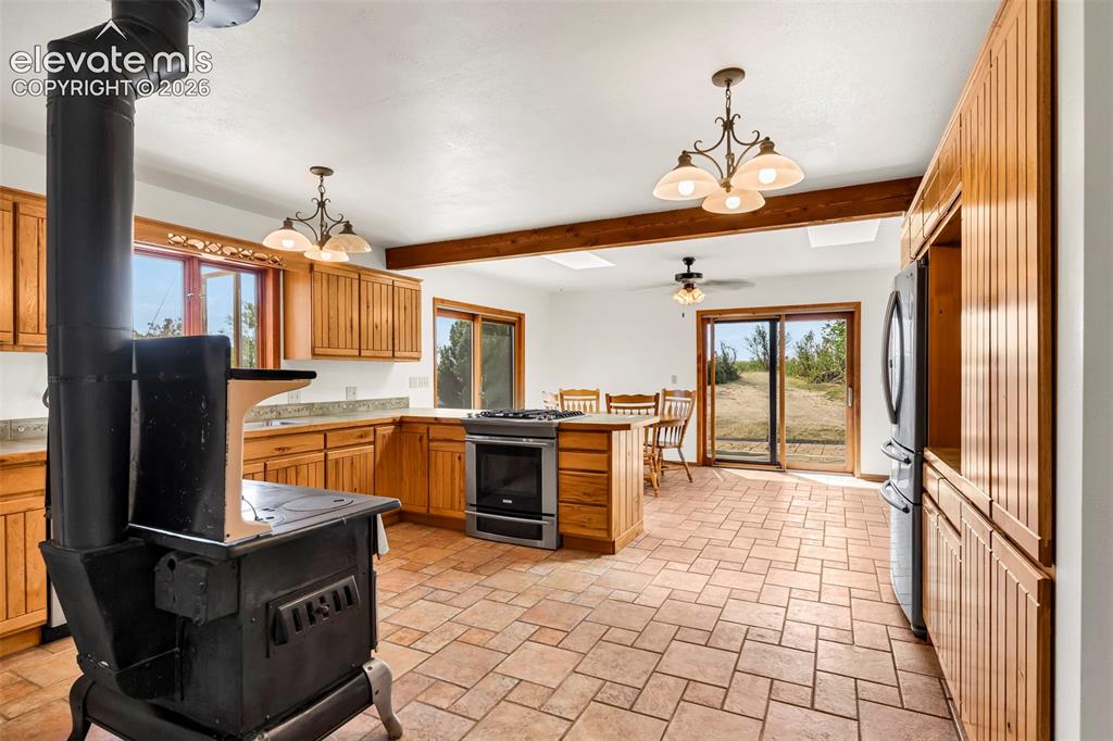 Image 11 of 49: Spacious kitchen featuring warm wood cabinetry, stone countertops, a freest