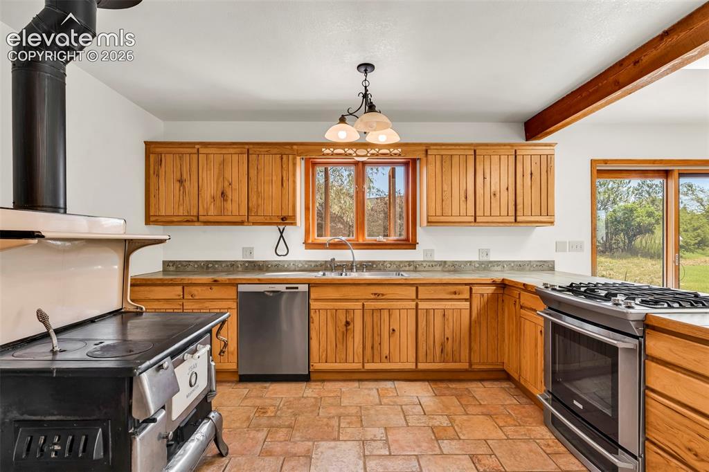 Image 13 of 49: Kitchen featuring wood cabinetry, stone countertops, stainless steel applia