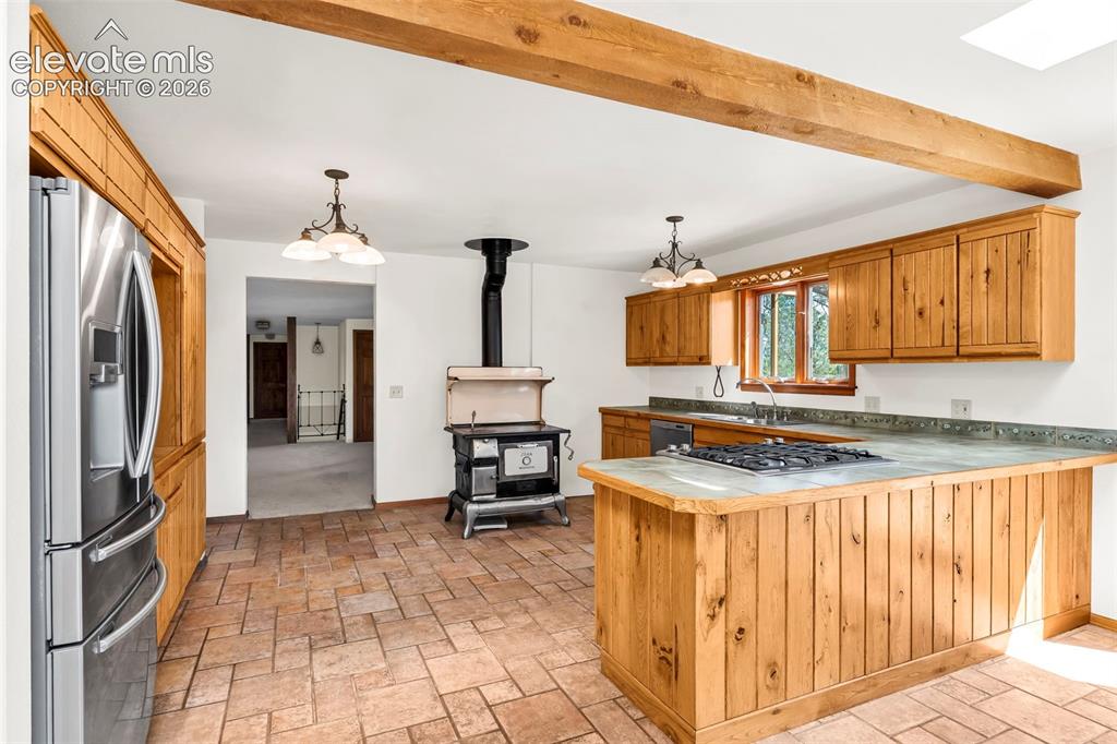 Image 14 of 49: Kitchen featuring wood cabinetry, stainless steel refrigerator, tile floori