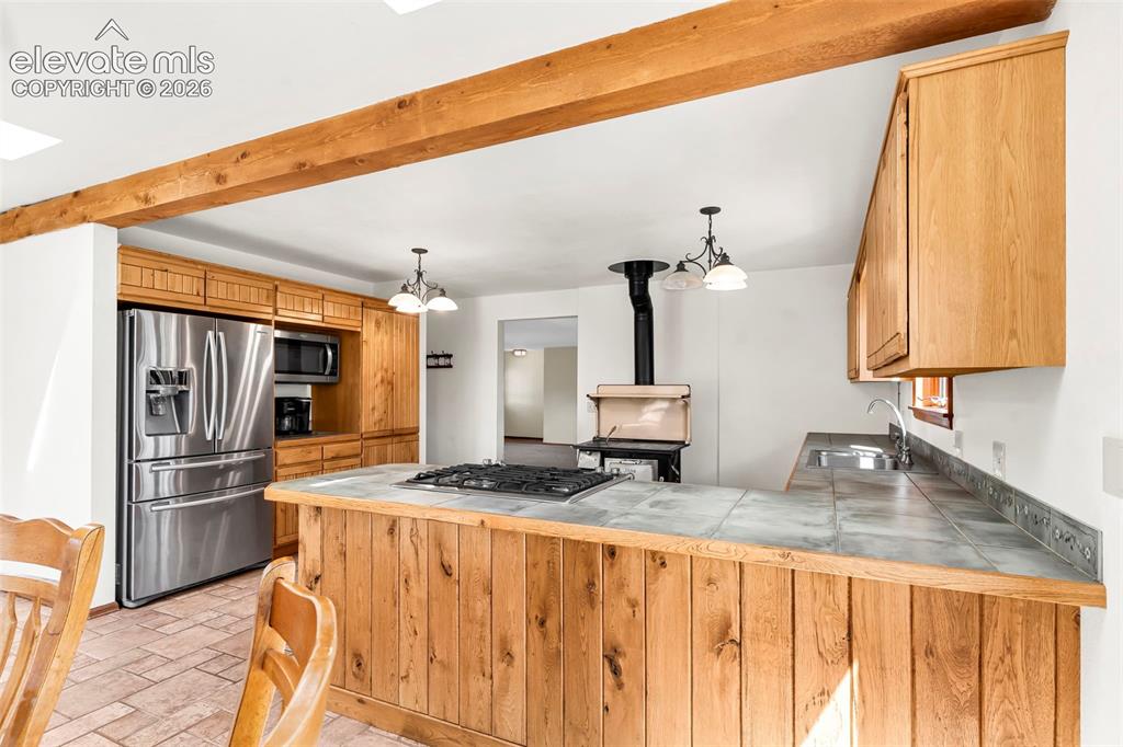 Image 15 of 49: Kitchen featuring a tiled countertop island with integrated gas cooktop, na