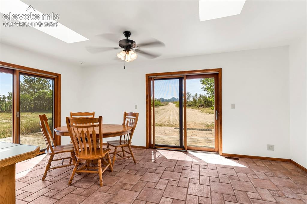Image 16 of 49: Bright interior space featuring two skylights, a ceiling fan, and white wal