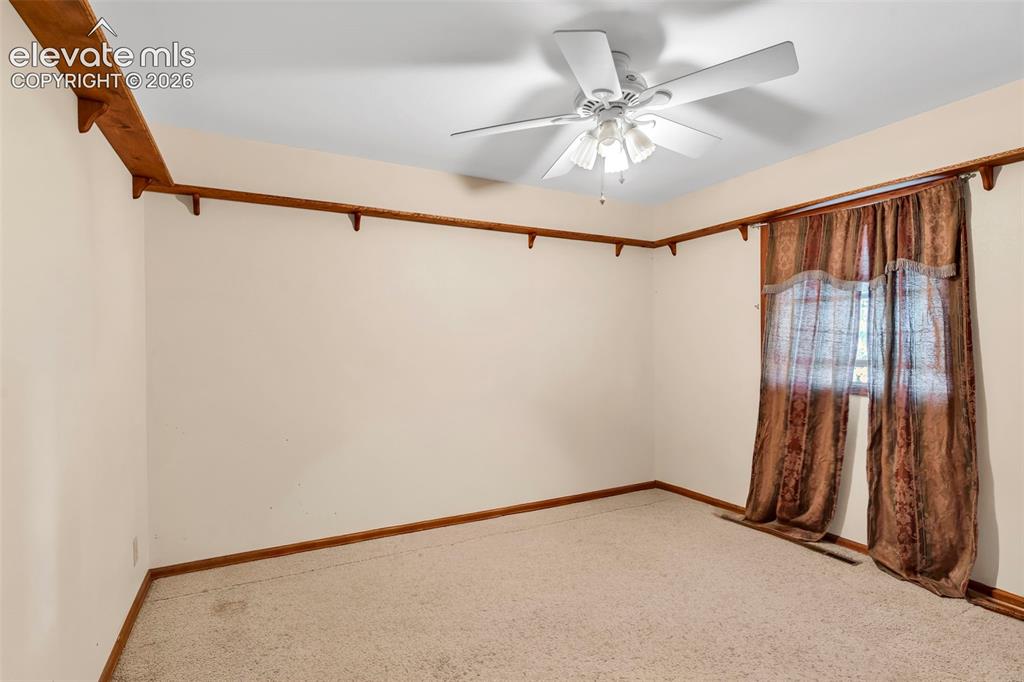 Image 19 of 49: Carpeted room featuring a ceiling fan with light fixture, wood trim, and a