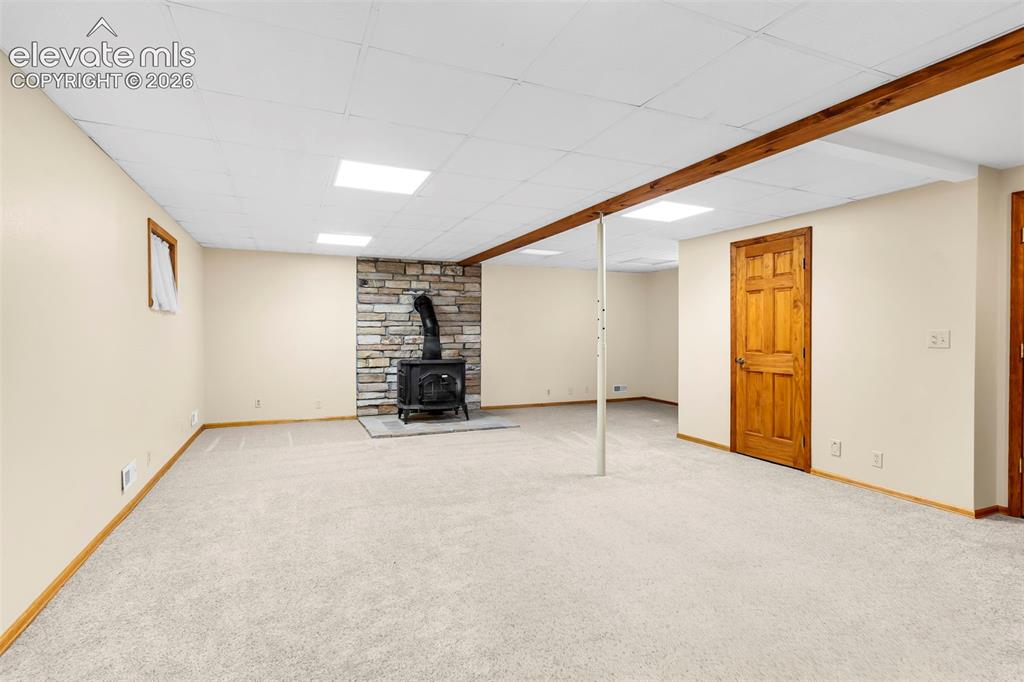 Image 23 of 49: Spacious room featuring light-colored carpet, a stone-clad wall with a blac