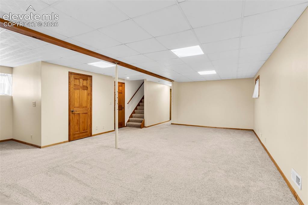 Image 25 of 49: Spacious carpeted room featuring a drop ceiling with integrated lighting, w